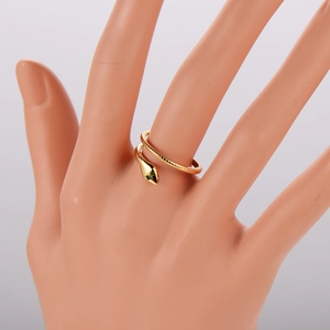 Detail of a vintage golden snake ring with green gem eyes and scale texture on finger