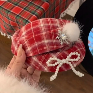 Detail of red plaid hat hair clip with pearl bow, diamond snowflake, and white pompom decor