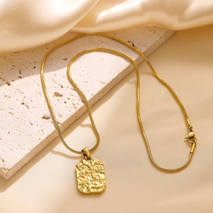 Close-up of a gold-plated square pendant with hammered texture on a snake chain