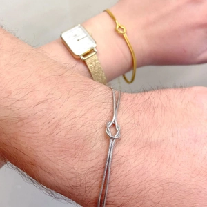 Close-up of gold and silver snake chain bracelets with knotted design worn on wrists