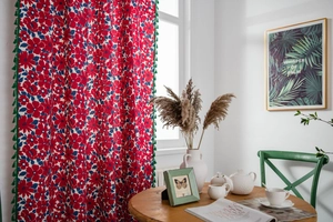 Detail of red floral cotton linen curtain with blue flower print and green tassel fringe