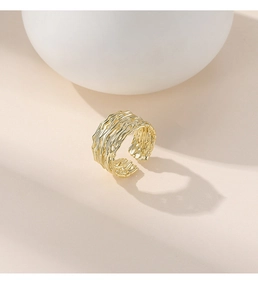 Macro detail of the irregular textured surface on this wide golden 925 silver open ring