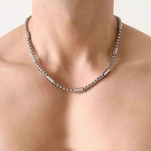 Silver stainless steel chain necklace with textured cylindrical accents on male model