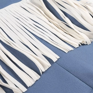 Close-up of blue wool jacket featuring long white decorative fringe and soft texture
