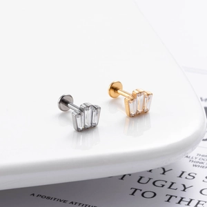 Detail of G23 titanium labret studs with baguette-cut zircon in silver and gold finishes
