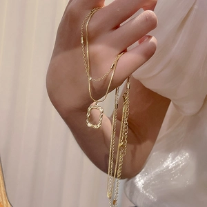 Detail of hand-held gold titanium necklace with hollow irregular geometric pendant charm