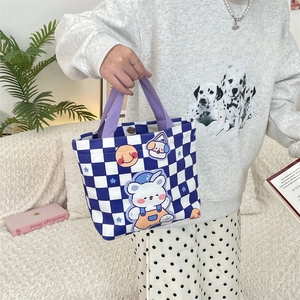 Detail of canvas tote bag featuring navy checkerboard pattern and cute cartoon patches
