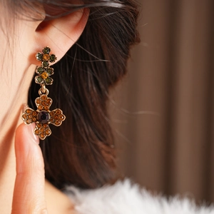 Gros plan de boucles d'oreilles croix vintage avec pierres marron et orange sur un mannequin