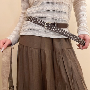Close-up of vintage brown leather belt featuring silver stud rivets and a horseshoe buckle