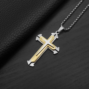 Macro detail of layered silver and gold cross pendant with a metallic box chain