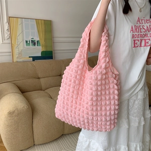 Pink bubble textured puff tote bag held by a model in a cozy indoor lifestyle setting