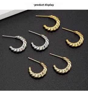 Detailed view of C-shaped twisted rope stud earrings in gold and silver metal finishes