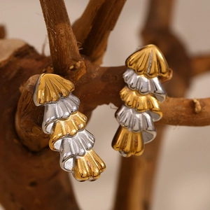 Macro view of Christmas tree-shaped gold and silver layered stainless steel earrings