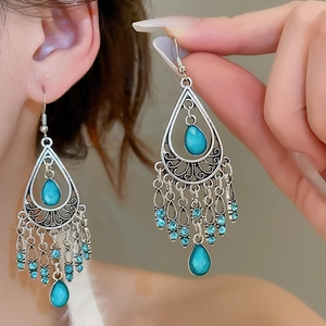 Detail of vintage bohemian silver earrings with blue teardrop stones and tassels