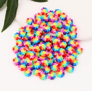 Vibrant colorful clay flower beads for DIY jewelry making scattered on white surface
