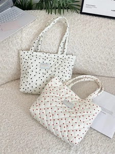 Quilted tote bags with heart patterns in black and red on a cozy white desk background