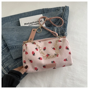 Close-up of pink corduroy shoulder bag with strawberry print and gold chain strap