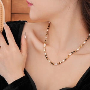 Primo piano di una collana di perle vintage con perline dorate indossata da una modella