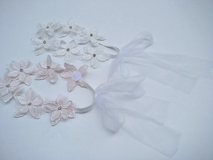 Dettaglio di fasce per neonati in pizzo bianco e rosa con strass e fiocchi
