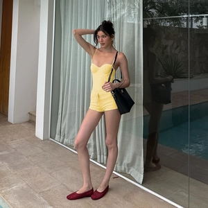 Close-up of bright yellow knitted two-piece set with striped texture and waist tie