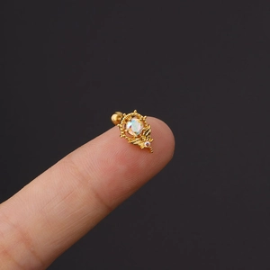 Makroaufnahme eines goldenen Edelstahl-Ohrsteckers mit Opal und Blattanhänger auf der Fingerspitze