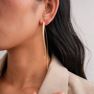 Close-up of model wearing minimalist 18K gold plated wavy drop earrings with sleek metallic finish