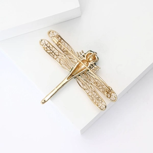 Detailed back view of a gold dragonfly brooch showing secure safety pin and metallic finish