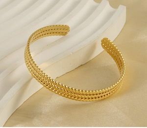 Detail of 18K gold plated cuff bracelet with vintage wheat grain pattern and hollow edges