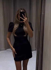 Detail of a chic black puff sleeve mini dress shown in a fitting room mirror selfie