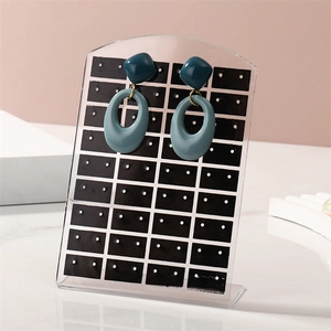 Teal geometric earrings hanging on a black acrylic 72-hole stud display organizer