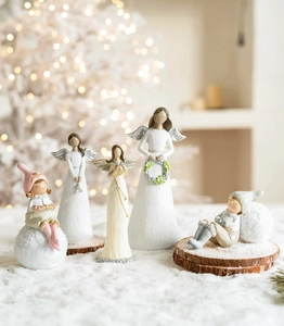 Detailed view of miniature resin Christmas angels and children on a snowy wooden base