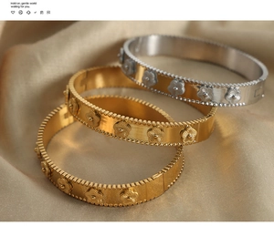 Detail of three stackable 18k gold and silver clover bracelets with beaded edges