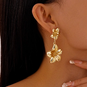 Nahaufnahme eleganter goldener Doppelblumen-Ohrhänger, an einem Modell getragen