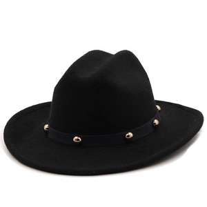 Close-up of black felt fedora hat featuring a gold studded band detail on white background