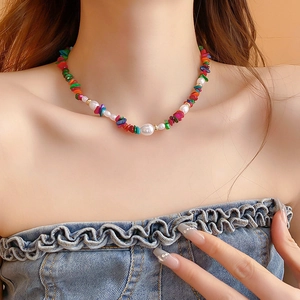 Close-up of colorful irregular stone and imitation pearl necklace on a model's neck
