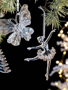 Glittery gold butterfly and ballerina acrylic Christmas ornaments on a pine branch