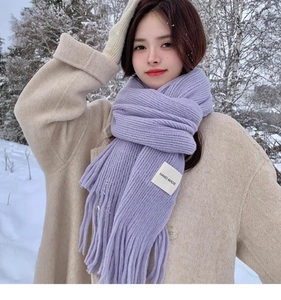 Close-up of thick light purple knitted scarf with fringe tassels in winter snow scene