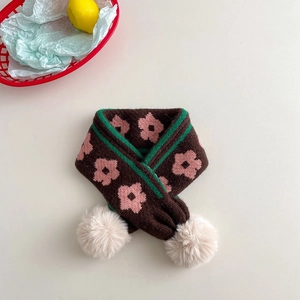 Detailed texture of knitted scarf with floral patterns and white pom-pom pendants