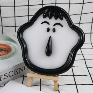 Close-up of creative cartoon face storage tray on a wooden tripod stand with art book