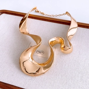 Macro detail of golden irregular wavy metal necklace with adjustable chain on a tray