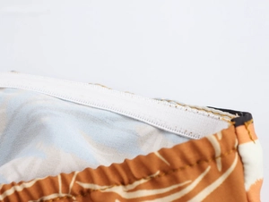 Detail view showing non-slip silicone strip on palm tree print strapless dress hem