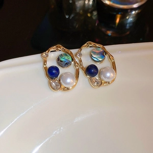 Detailed close-up of gold petal earrings with pearls, blue beads and zircon crystals