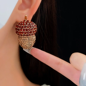 Macro shot of vintage gold acorn earrings with red and champagne crystals