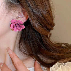 Gros plan de boucles d'oreilles fleurs 3D roses montrant la texture et la taille