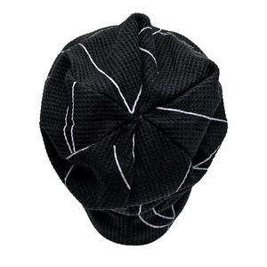 Macro detail of black waffle knit beanie showing elastic texture and white geometric pattern