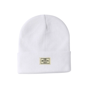 Detailed view of white ribbed knit beanie featuring a stitched Brooklyn N°86 woven patch
