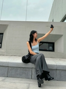 Outdoor street style view of light blue tie-up vest paired with dark grey wide-leg pants