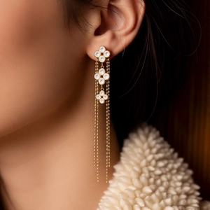 Close-up of elegant gold plated flower tassel earrings with zircons worn by a model