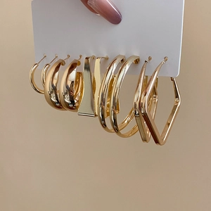 Macro view of gold geometric hoop earrings set with polished finish on display card