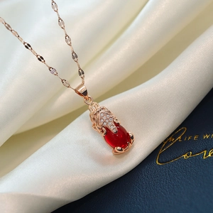 Macro view of gold plated PiXiu pendant with a red oval stone and sparkling white diamonds